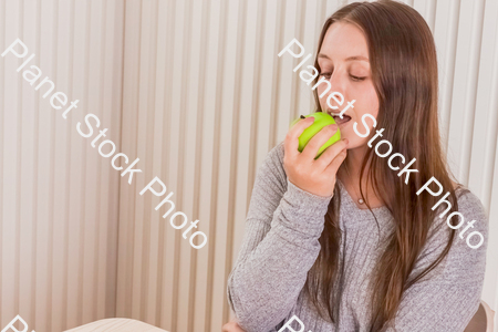 A girl sitting with an apple in her hand stock photo with image ID: 96227345-00e9-4a90-be7e-ecadcbdd27c0