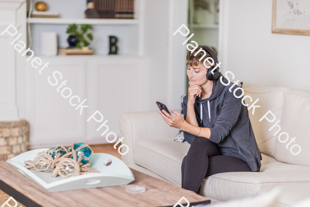 A young lady sitting on the couch stock photo with image ID: a6ac0a11-d88a-490e-ac75-a87b9e5c59db