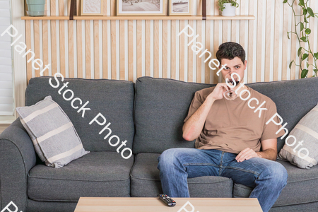 A young man sitting on the couch, watching a TV, and enjoying red wine stock photo with image ID: a8703721-bcd2-4965-bb05-7db5090d414d