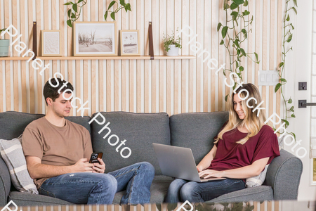 A young couple sitting on the couch stock photo with image ID: cb9c9dee-dc18-478e-90f4-ed522b347ca4
