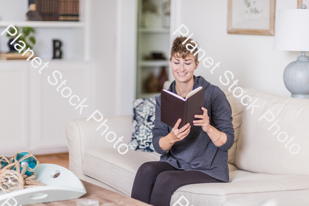 A young lady sitting on the couch stock photo with image ID: cf1eb4b2-e82f-4707-ac78-0860547fcdd5
