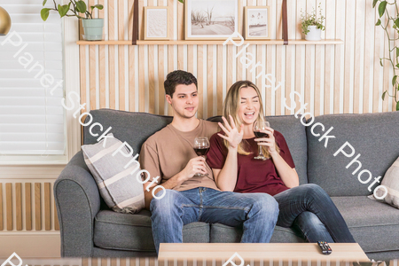 A young couple sitting on the couch and enjoying red wine stock photo with image ID: d4176b69-f9fb-4cfa-90b4-f110d9cf80a2