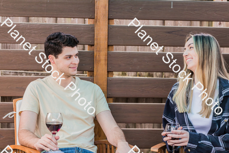 A young couple sitting outdoors, enjoying red wine stock photo with image ID: d5ed4b76-103d-498d-85fd-5d1d9e230c7a