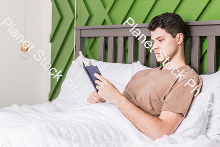 A young man reading in bed stock photo with image ID: d6fc7602-07b2-4ea6-8830-02607da9705f