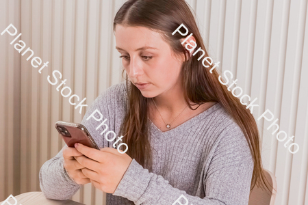 A girl sitting and using a mobile phone stock photo with image ID: daed0584-178a-40d3-a9d1-4bc28f7f75d6