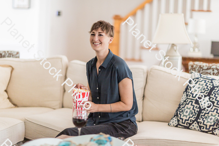 A young lady sitting on the couch watching a movie stock photo with image ID: de15a590-f30c-4ff9-8879-35df9bd32394
