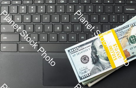 Three stacks of dollar bills on a laptop computer stock photo with image ID: dfbaf315-d630-4225-82f4-1a525296e2a8