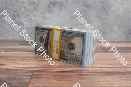 Three stacks of dollar bills, on a wood surface stock photo with image ID: e0ceeed9-2556-497e-ad52-10699e02a401
