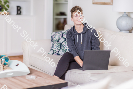 A young lady sitting on the couch stock photo with image ID: e11b31f6-5d0c-486a-a78d-15865c645884