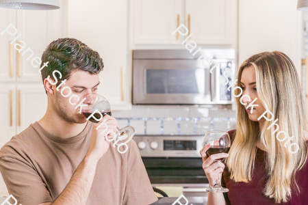 A young couple sitting and enjoying red wine stock photo with image ID: fd66107c-ad19-4429-aae7-367274182cf6