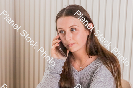 A girl sitting at the table, using a mobile phone stock photo with image ID: 784fd2bc-8316-4401-8f82-a9ca73e1e4f9