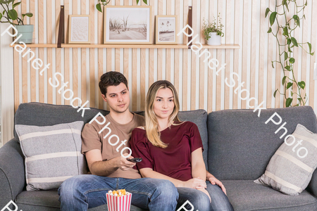 A young couple sitting on the couch watching a movie stock photo with image ID: fd71ba55-b5e2-48cd-b751-f53896b096c0