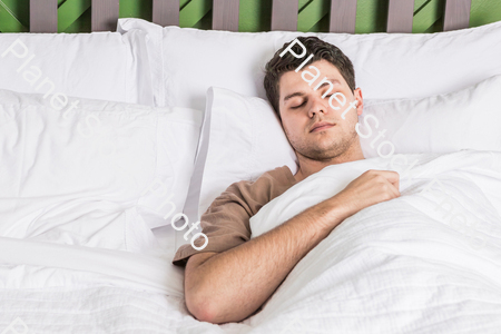 A young man sleeping in bed stock photo with image ID: cb8e8c23-d7f0-4334-88ee-b81f2aad665e