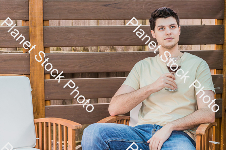 A young man sitting outdoors enjoying red wine stock photo with image ID: 5b87a743-4a1c-41d1-8702-3804bbebe90c