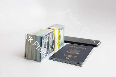 Three stacks of dollar bills, a US passport, and mobile phone stock photo with image ID: 685df657-61b8-4292-b42d-e70d605904bf