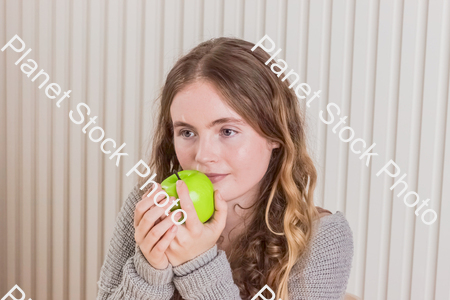 A girl sitting at the table, eating an apple stock photo with image ID: 15c152c2-36fe-4912-8ba3-475bd5369e46