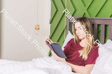 A young woman reading in bed stock photo with image ID: 28ac632d-5cfc-482f-a4c9-928f5ec2de0b