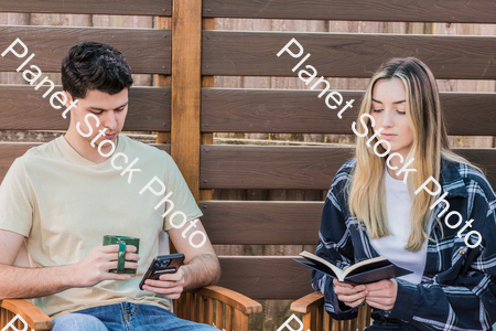 A young couple sitting outdoors stock photo with image ID: 43bc6e71-b57f-400c-8ba1-b5a2c5527b0d