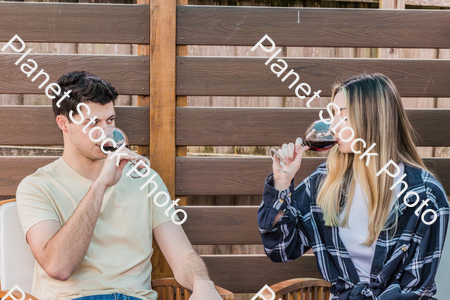 A young couple sitting outdoors, enjoying red wine stock photo with image ID: 60de6a67-1575-4a63-a408-ff51a543bc99