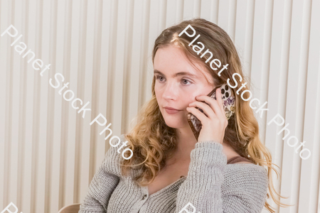 A girl sitting at the table, using a mobile phone stock photo with image ID: 42f134c2-b6f2-4e3f-87b5-19b5d64d2bd5