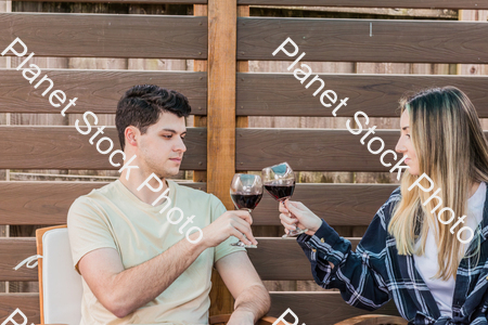 A young couple sitting outdoors, enjoying red wine stock photo with image ID: 941c99e7-1af5-4040-8717-39754abe870c