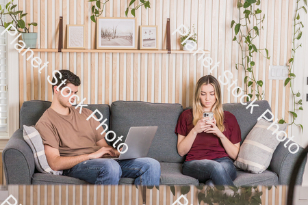 A young couple sitting on the couch stock photo with image ID: d9781ed3-078a-425f-9174-03874b6dc240