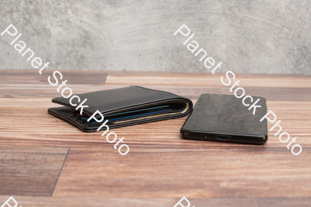 A mobile phone, with a black leather wallet stock photo with image ID: 220a463e-0d85-4f75-84a0-2dc5edba92b6