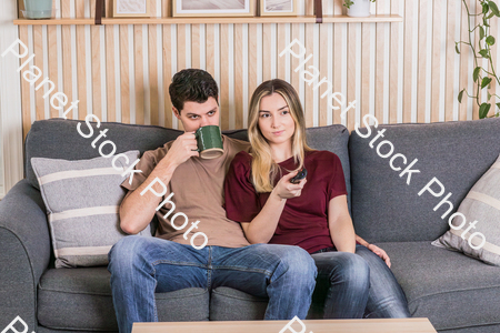 A young couple sitting on the couch watching a movie stock photo with image ID: f1bf9349-b36d-4e43-8a4a-4fd8bf7d4303