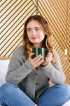 A girl sitting on the bed and enjoying a hot drink