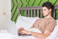 A young man in bed using a laptop