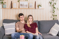 A young couple sitting on the couch watching a movie