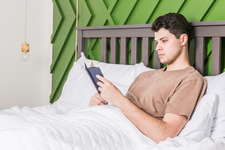 A young man reading in bed