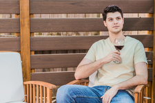 A young man sitting outdoors enjoying red wine