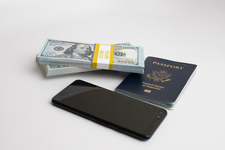 Three stacks of dollar bills, with  a US passport, and mobile phone