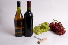 Two bottles of wine, with corkscrew, and grapes