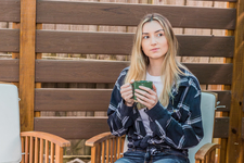 A young woman sitting outdoors enjoying a hot drink