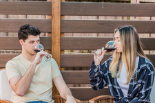 A young couple sitting outdoors, enjoying red wine