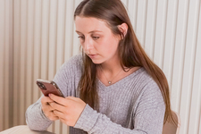 A girl sitting at the table, using a mobile phone