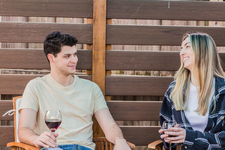 A young couple sitting outdoors, enjoying red wine