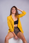 Model wearing yellow jacket, posing for a studio photoshoot