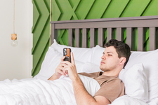 A young man in bed using a mobile phone