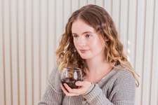 A girl sitting at the table, enjoying red wine
