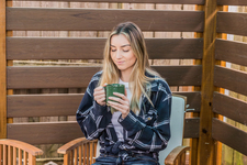 A young woman sitting outdoors enjoying a hot drink